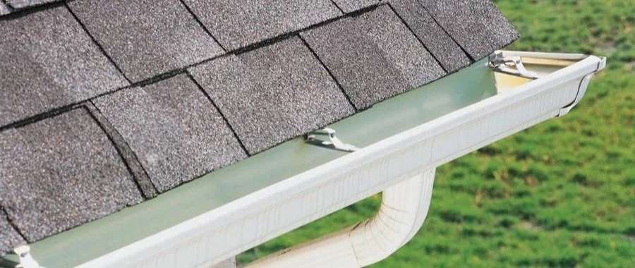 White seamless gutter along a shingle roofline