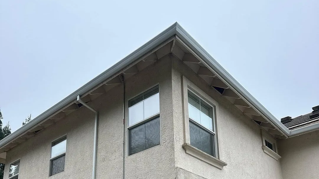 New seamless gutters on the corner of a two-story stucco home